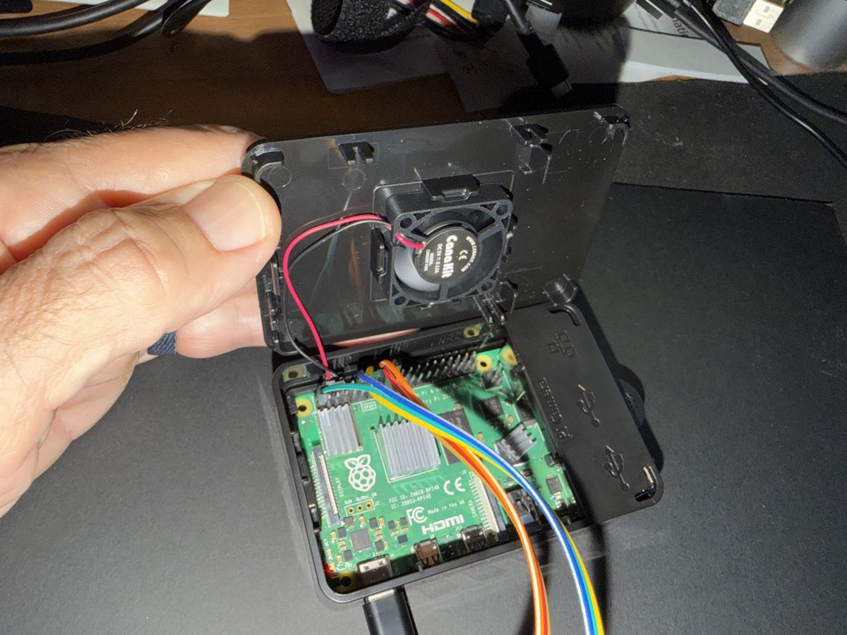 Open case with the fan in the lid and jumper wires on the Pi's GPIO pins